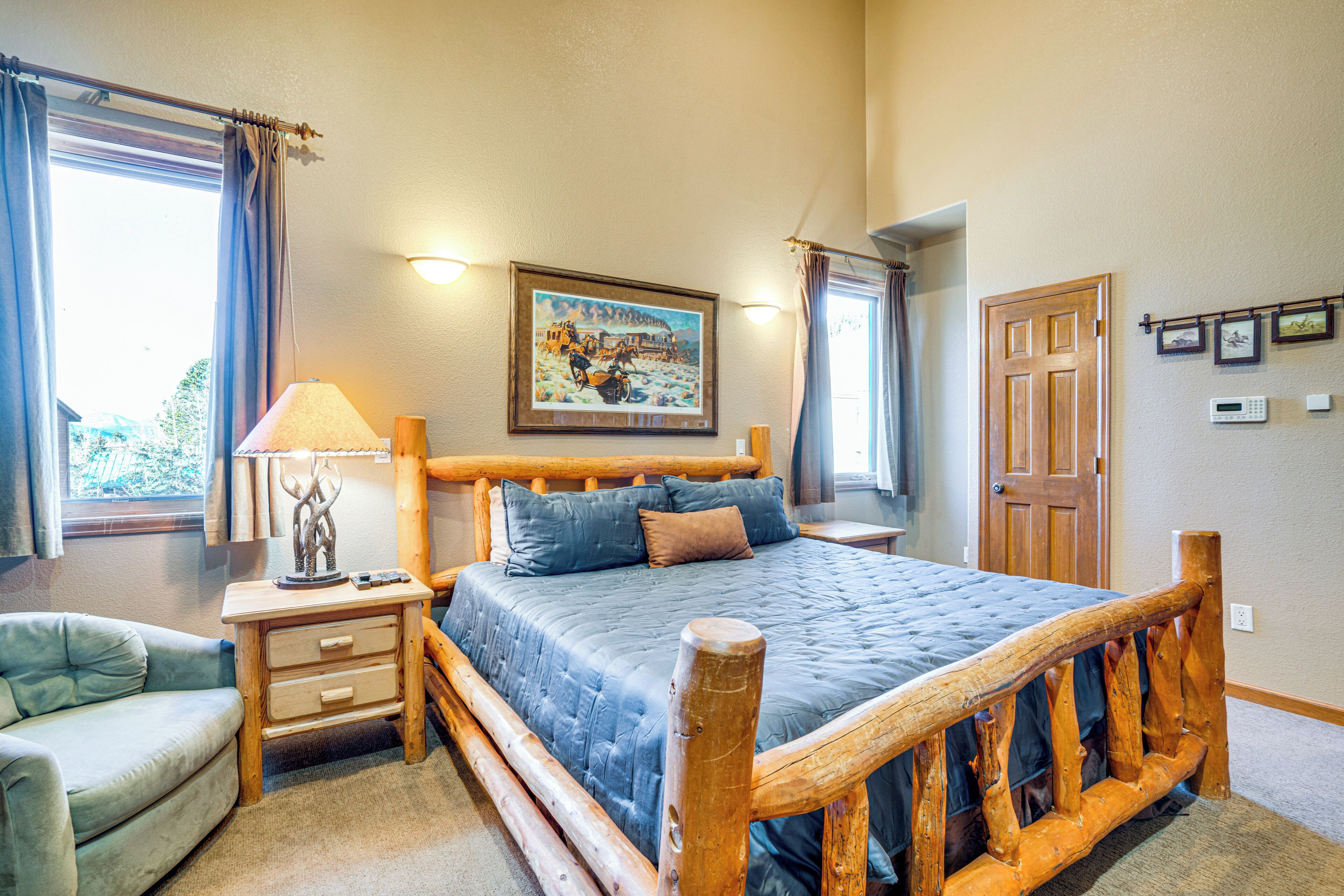 A bedroom with a wooden bed frame, a bedside table with a lamp, a chair, and a painting on the wall.