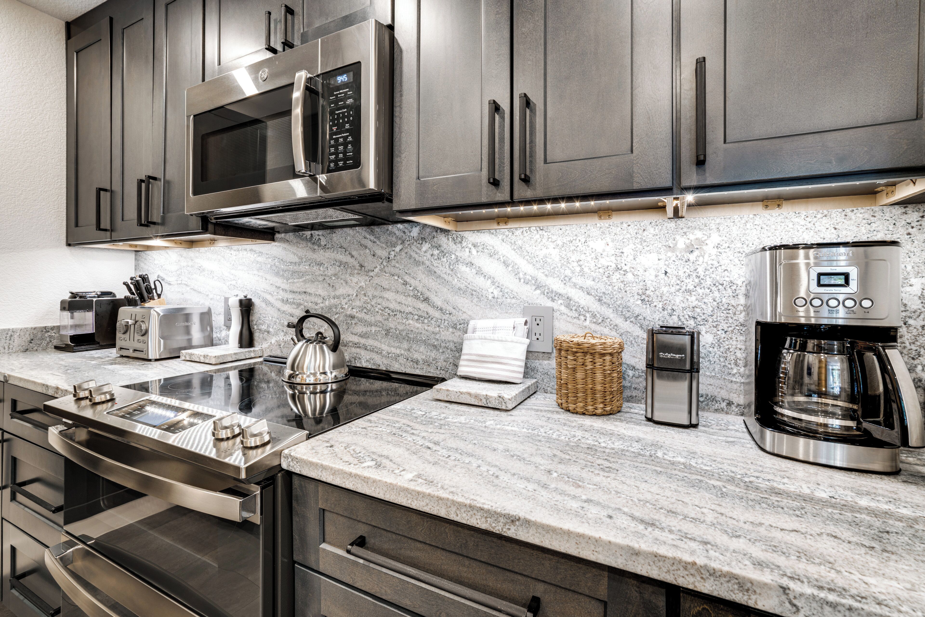 A modern kitchen with stainless steel appliances, a marble countertop, and a built-in oven.