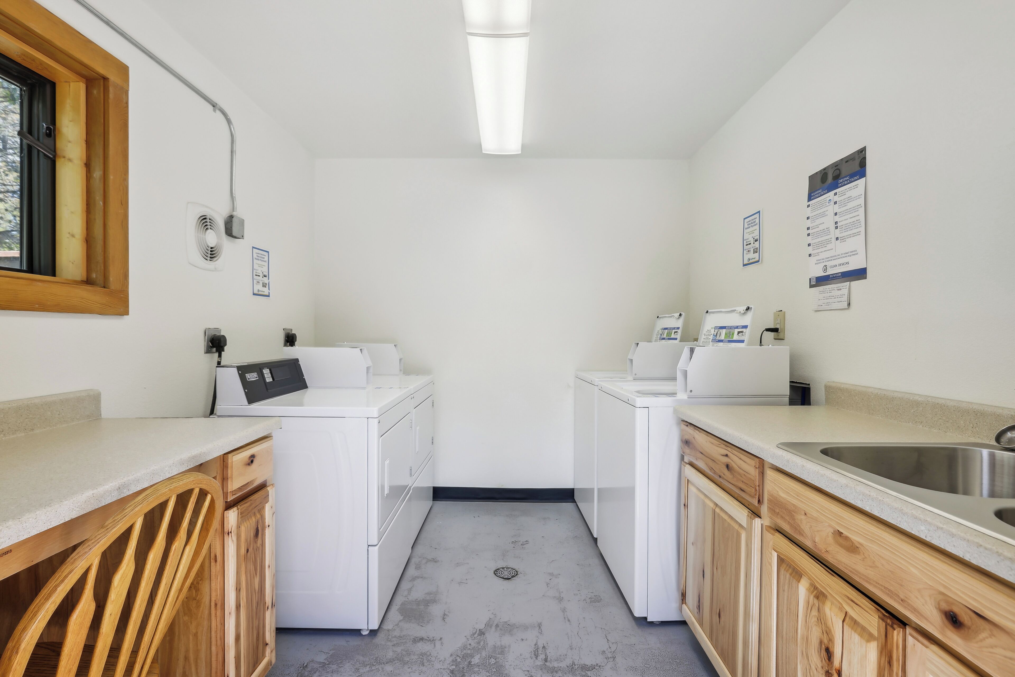 A compact kitchen with white appliances, wooden cabinets, and a large window.