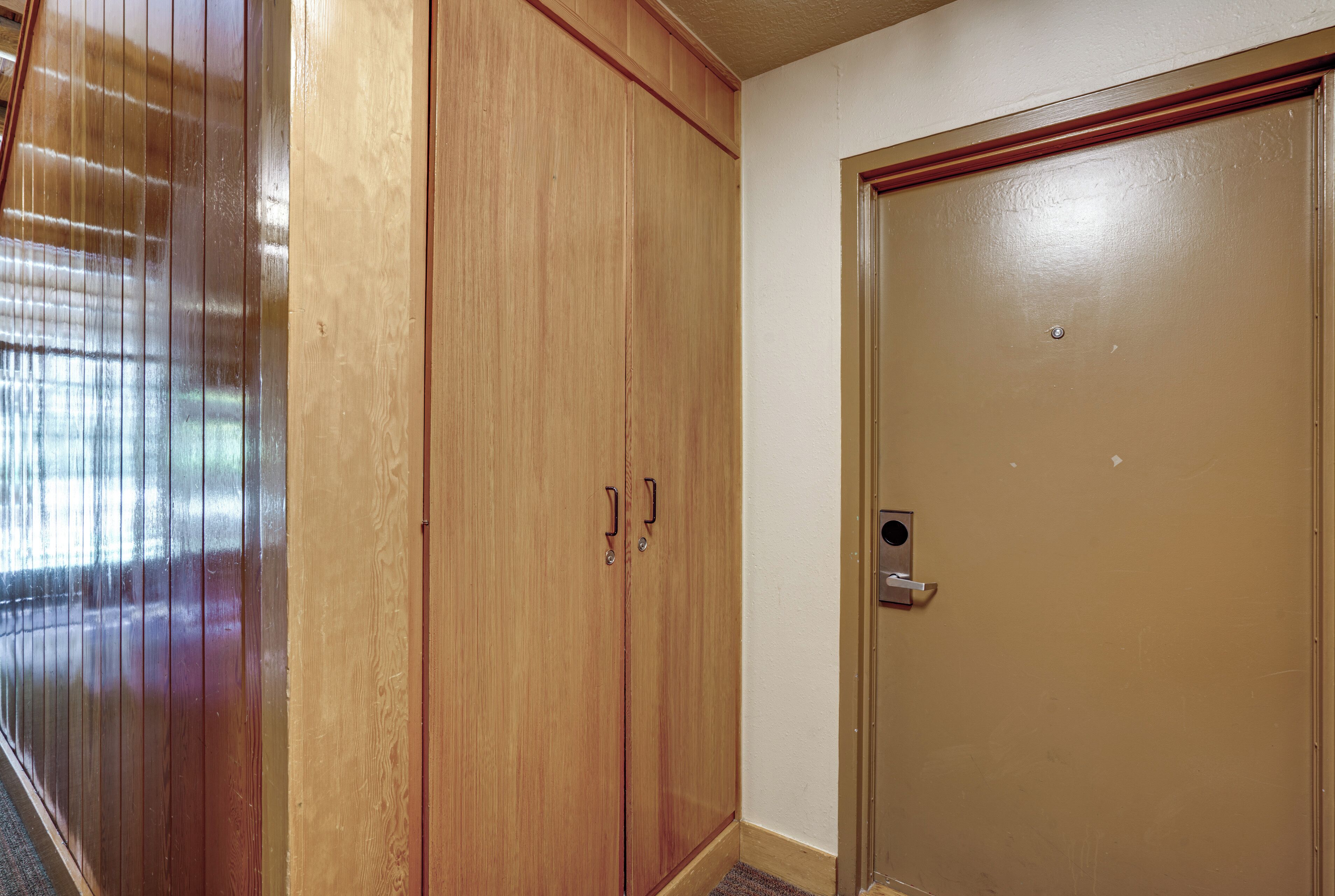 A wooden wardrobe with two doors and a small door to the right.