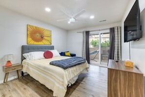 A modern bedroom with a bed, a ceiling fan, a TV, and a balcony with curtains.