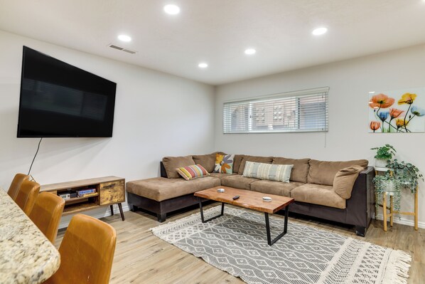 A modern living room with a sectional sofa, a wooden coffee table, and a TV mounted on the wall.