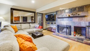 Een moderne woonkamer met een open haard, een grote spiegel en een hoekbank.