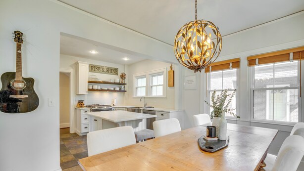 A modern kitchen with white cabinetry, a wooden dining table, and a guitar on the wall. - Charming Louisville Retreat w/ Patio & Fireplace! (Louisville)