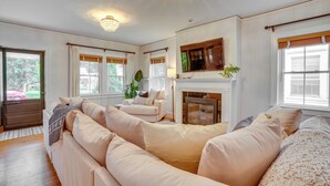 A spacious living room with a large beige sectional sofa, a fireplace, and a large window with curtains. - Charming Louisville Retreat w/ Patio & Fireplace! (Louisville)