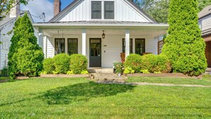 A white two-story house with a front porch, a chimney, and a well-maintained lawn. - Charming Louisville Retreat w/ Patio & Fireplace! (Louisville)