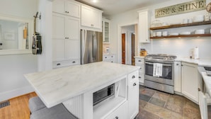 A modern kitchen with white cabinetry, stainless steel appliances, and a marble countertop. - Charming Louisville Retreat w/ Patio & Fireplace! (Louisville)