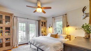 A bedroom with a bed, a ceiling fan, a bookshelf, and a large window. - Charming Louisville Retreat w/ Patio & Fireplace! (Louisville)