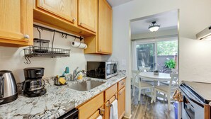 A kitchen with wooden cabinets, a granite countertop, a coffee maker, a microwave, and a sink. - Beautiful Boulder Townhome: Walk to CU & Pearl St! (Boulder)