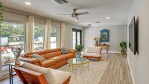 A spacious living room with a leather sofa, a wooden chair, a glass coffee table, and a ceiling fan. - Vero Beach Vacation Rental: Pool & Putting Green! (Vero Beach)