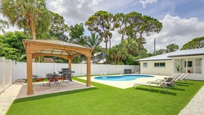 A backyard with a swimming pool, a covered patio, and a fenced area. - Vero Beach Vacation Rental: Pool & Putting Green! (Vero Beach)