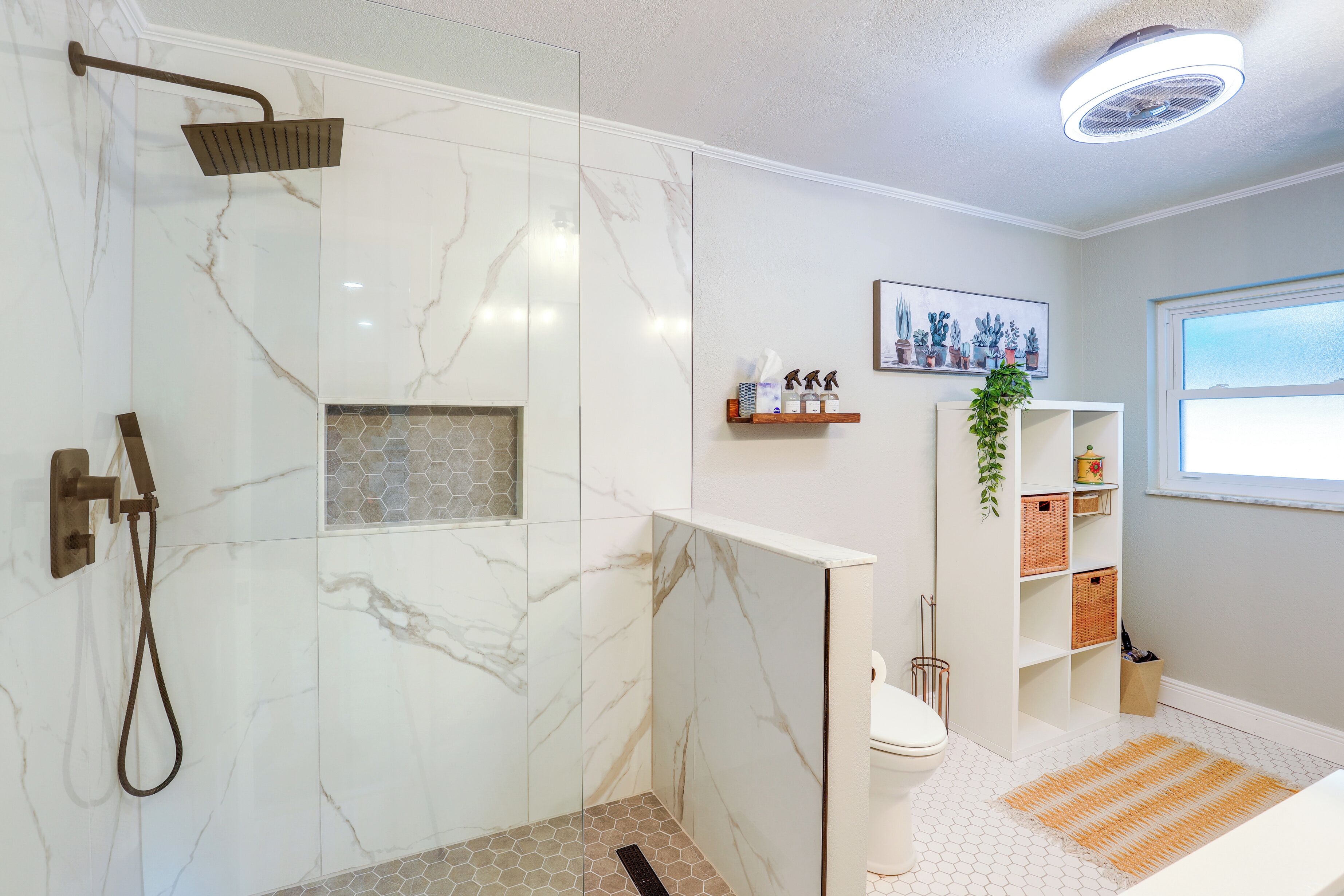 A modern bathroom with a shower, toilet, and a shelf with toiletries.