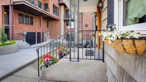 Un bâtiment en briques doté d’un balcon, d’une grille en métal et de jardinières au niveau du rez-de-chaussée.
