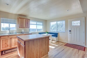 A kitchen with wooden cabinets, a large island, and a bench. - Comfy Oakhurst Duplex Near Hiking & Sightseeing! (Oakhurst)