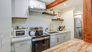 A kitchen with white cabinets, a stainless steel stove, a microwave, and a wooden countertop. - Updated Tacoma Home w/ Fire Pit! (Tacoma)