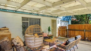 A covered patio area with wicker furniture, a wooden table, and a patterned rug. - Updated Tacoma Home w/ Fire Pit! (Tacoma)