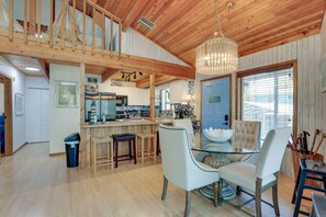 A spacious kitchen with wooden cabinets, a dining area with a glass table, and a bar area with stools. - Scenic Siesta Key Home ~ 1 Mi to Village & Beach! (Siesta Key)