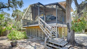 A house with a large glass enclosure, wooden deck, and a staircase leading to a balcony. - Scenic Siesta Key Home ~ 1 Mi to Village & Beach! (Siesta Key)