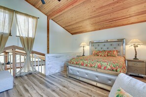 A bedroom with a wooden ceiling, a bed with a floral bedspread, two bedside lamps, and a view of a balcony. - Scenic Siesta Key Home ~ 1 Mi to Village & Beach! (Siesta Key)