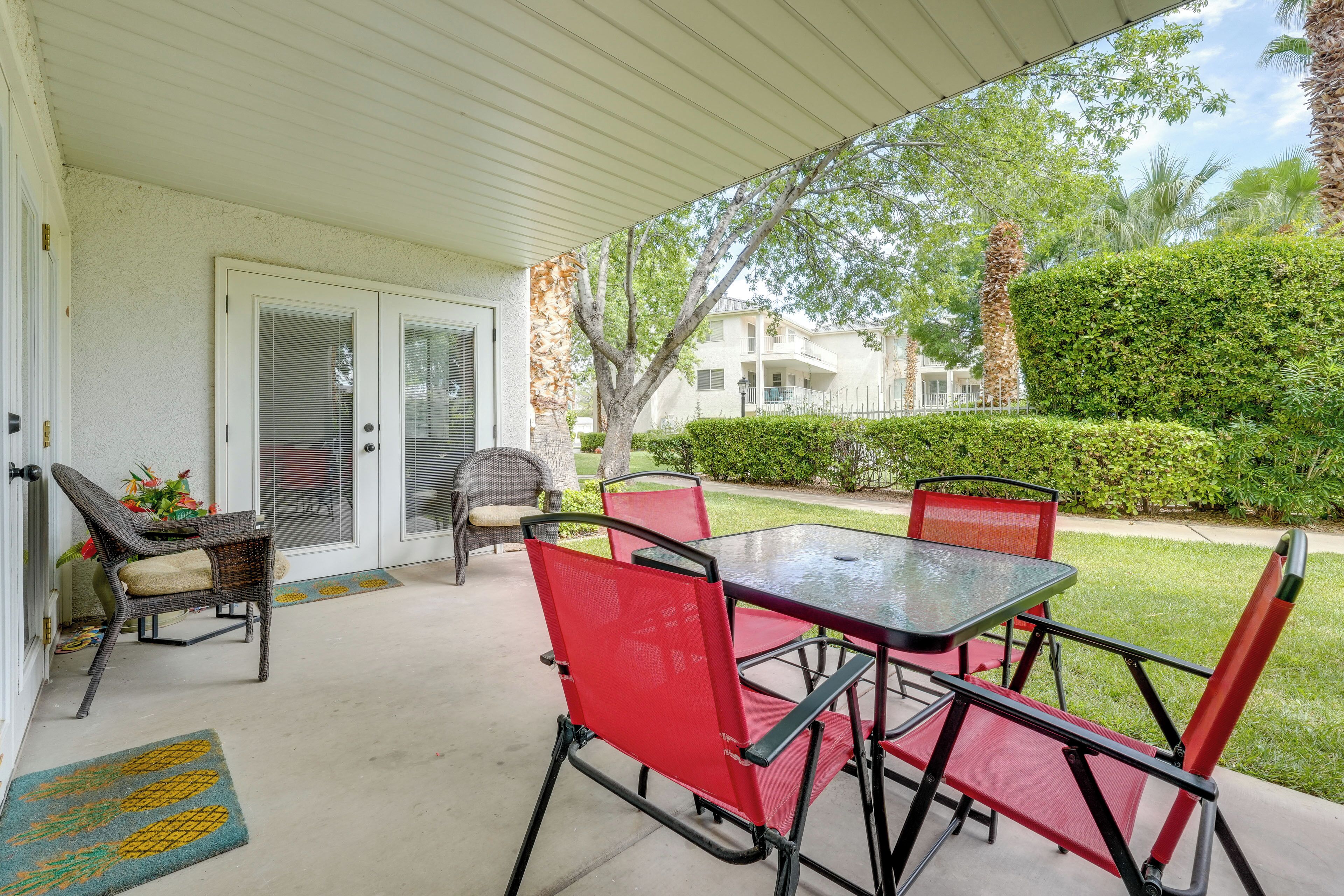 Une terrasse couverte avec une table et des chaises, une porte et un petit espace jardin.