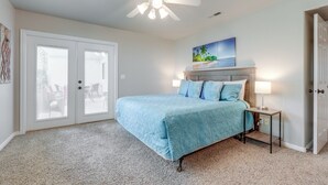 A bedroom with a bed, a ceiling fan, a nightstand with a lamp, and a door. - Family-friendly St George Condo w/ Community Pools (St. George)