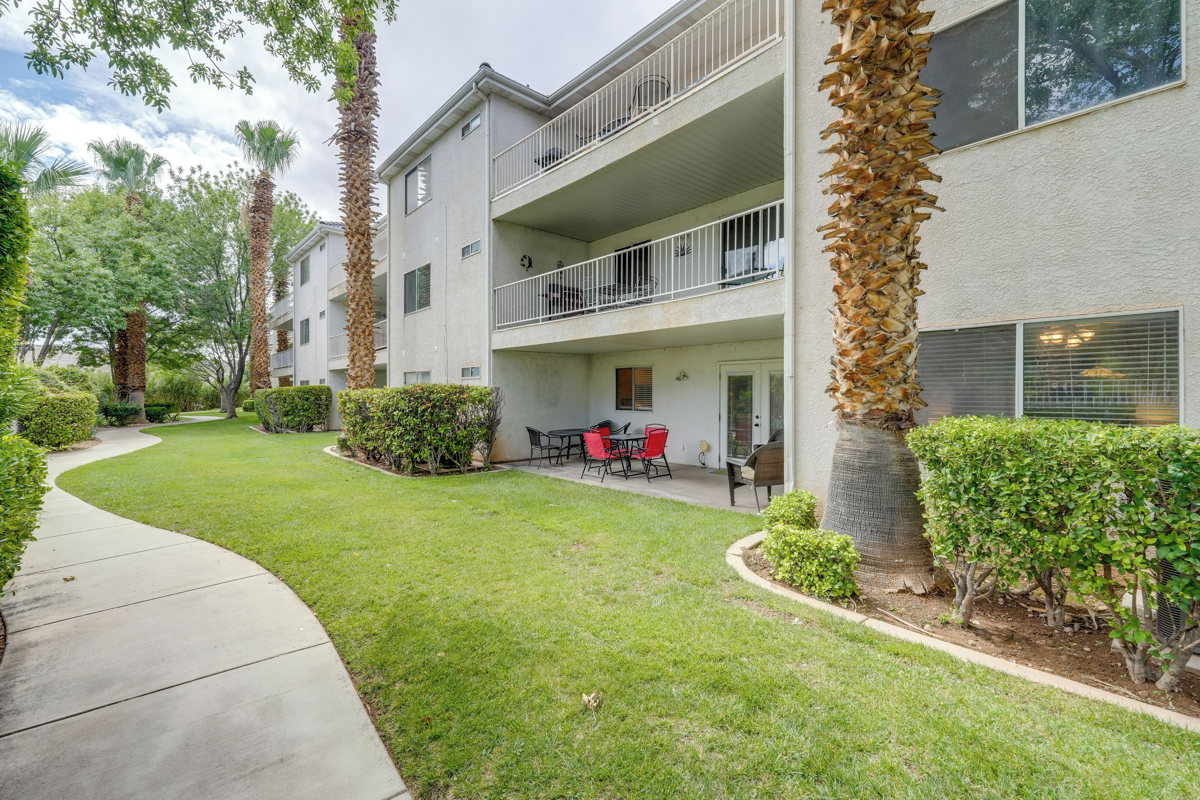 A multi-story residential building with a covered outdoor seating area, surrounded by well-maintained lawns and palm trees.