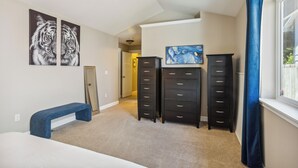 A bedroom with a bed, a bench, two black dressers, a ceiling fan, and artwork on the walls. - Cheery Tacoma Vacation Rental: 7 Mi to Owen Beach! (Tacoma)