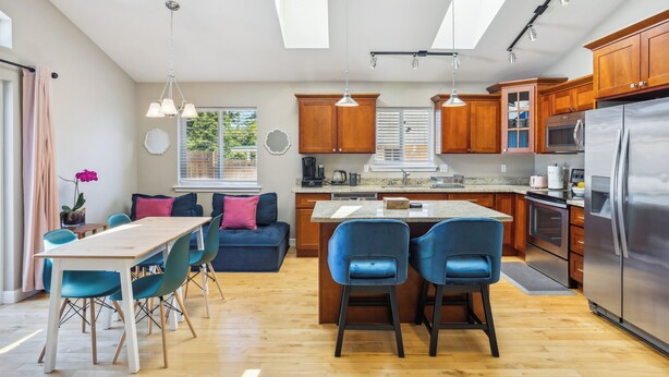 A modern kitchen with wooden cabinets, a stainless steel refrigerator, and a central island with bar stools. - Cheery Tacoma Vacation Rental: 7 Mi to Owen Beach! (Tacoma)