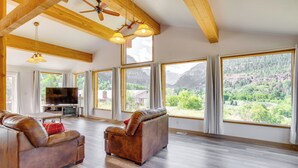 A spacious living room with two leather sofas, a flat-screen TV, and large windows offering mountain views. - Stunning Ouray Escape w/ Panoramic Mountain Views! (Ouray)