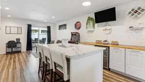 A modern kitchen with a central island, white cabinetry, and a flat-screen TV mounted above the island. - Charming Tacoma Retreat w/ Patio & 2 Fireplaces! (Tacoma)