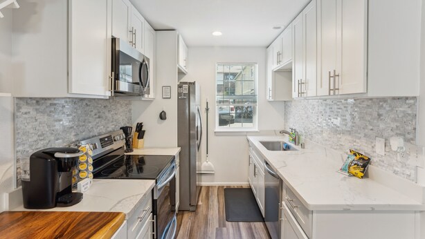 A modern kitchen with white cabinets, a built-in microwave, a stainless steel refrigerator, and a coffee maker. - Charming Tacoma Retreat w/ Patio & 2 Fireplaces! (Tacoma)