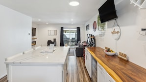 A modern kitchen with a white island, wooden countertop, and a TV mounted on the wall. - Charming Tacoma Retreat w/ Patio & 2 Fireplaces! (Tacoma)