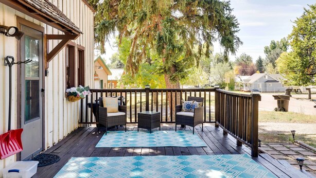 A wooden deck with wicker furniture, a blue patterned rug, and a hanging flower basket. - Cottage w/ Furnished Deck: 1 Mi to Dtwn Craig! (Craig)