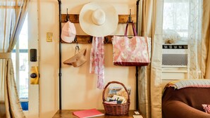 A room with a wooden wall-mounted rack holding bags and a hat, a wicker basket with items, a pink folder, and a brown sofa. - Cottage w/ Furnished Deck: 1 Mi to Dtwn Craig! (Craig)