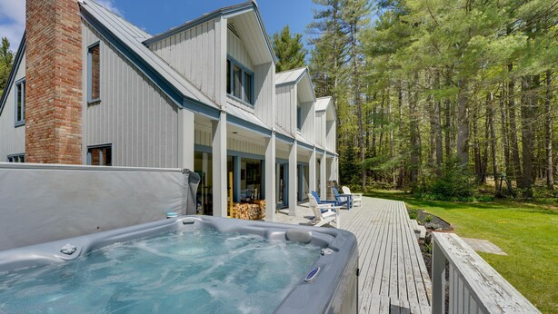 A modern house with a hot tub, wooden deck, and a forested area. - Mendon Home w/ Hot Tub, Fire Pit & Near Skiing! (Rutland)