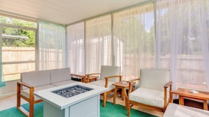 A sunlit room with a sofa, chairs, a small table, and a charcoal grill. - Fenced & Private Backyard: Navarre Retreat (Navarre)