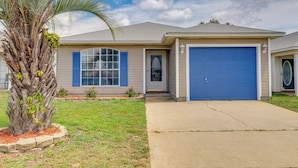 A single-story house with a blue garage door, a front entrance with a door, and a palm tree in the front yard. - Fenced & Private Backyard: Navarre Retreat (Navarre)