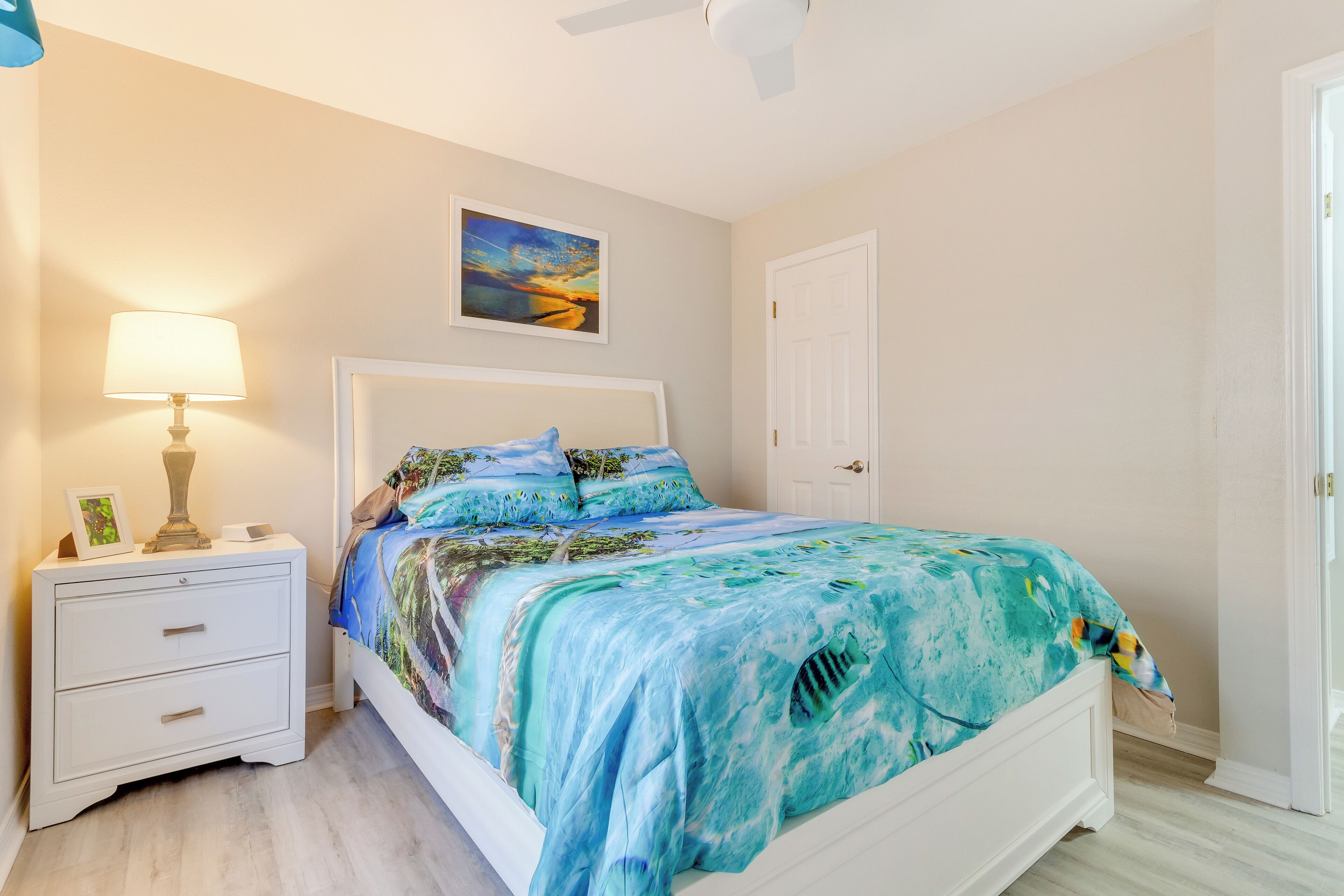 Un dormitorio con cama, mesita de noche y un cuadro en la pared.