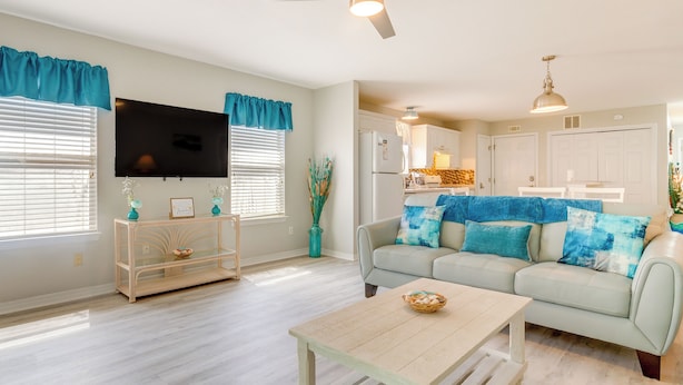 A living room with a light-colored sofa, a coffee table, and a TV. - Fenced & Private Backyard: Navarre Retreat (Navarre)