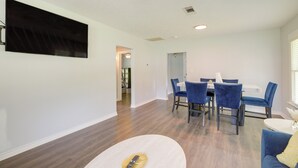 Een moderne woonkamer met een eethoek, houten vloeren en een plafondventilator.