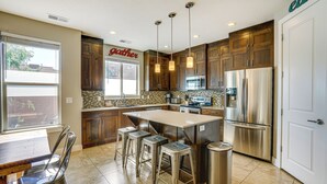 A modern kitchen with wooden cabinets, stainless steel appliances, and a large island with bar stools. - Moab Vacation Rental: Pool & Hot Tub Access! (Moab)