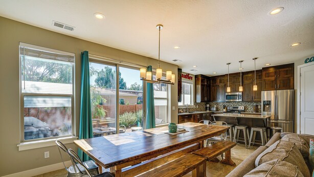 A spacious kitchen with a wooden dining table, bar stools, and a built-in oven. - Moab Vacation Rental: Pool & Hot Tub Access! (Moab)