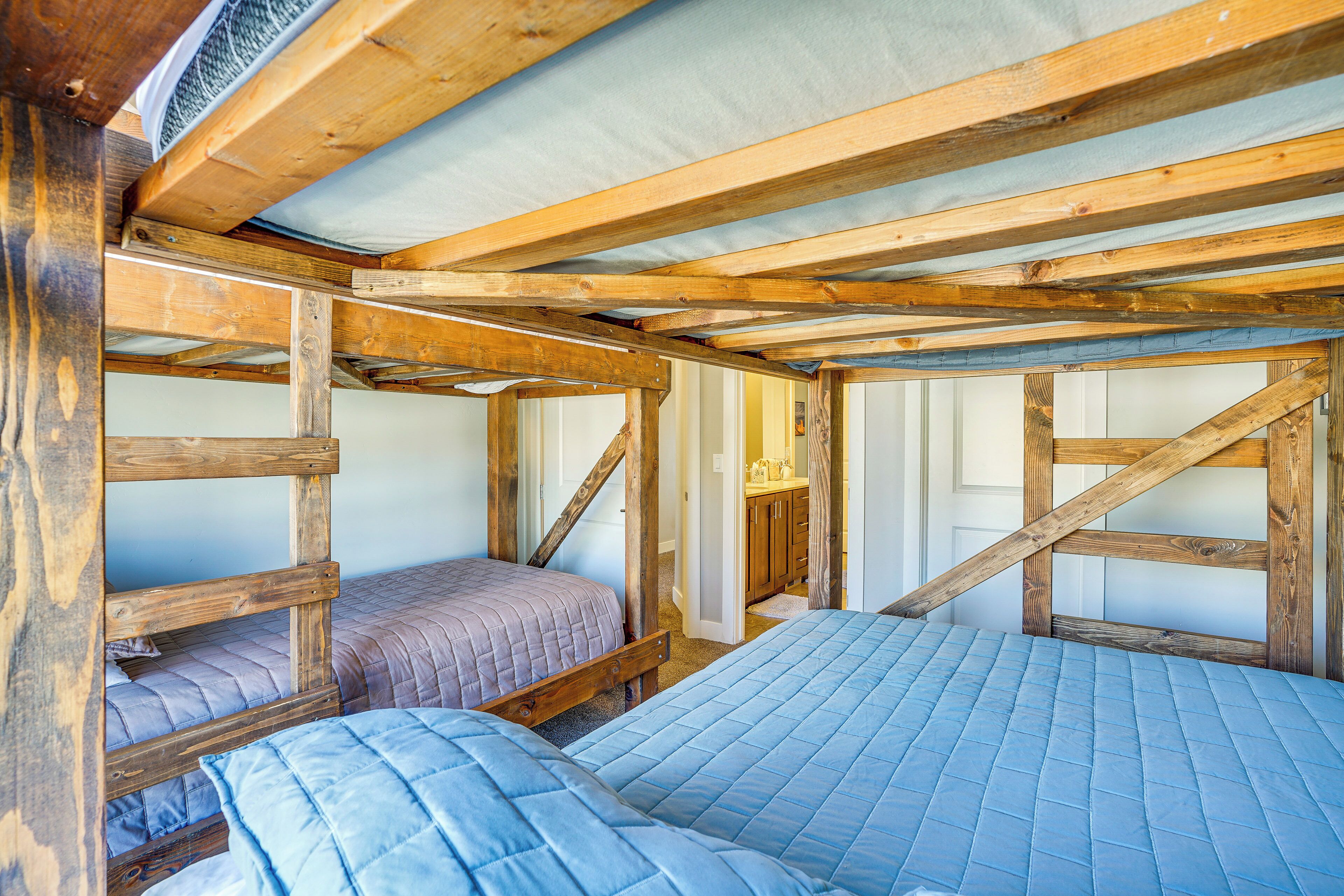 A rustic wooden room with bunk beds and a visible bathroom.