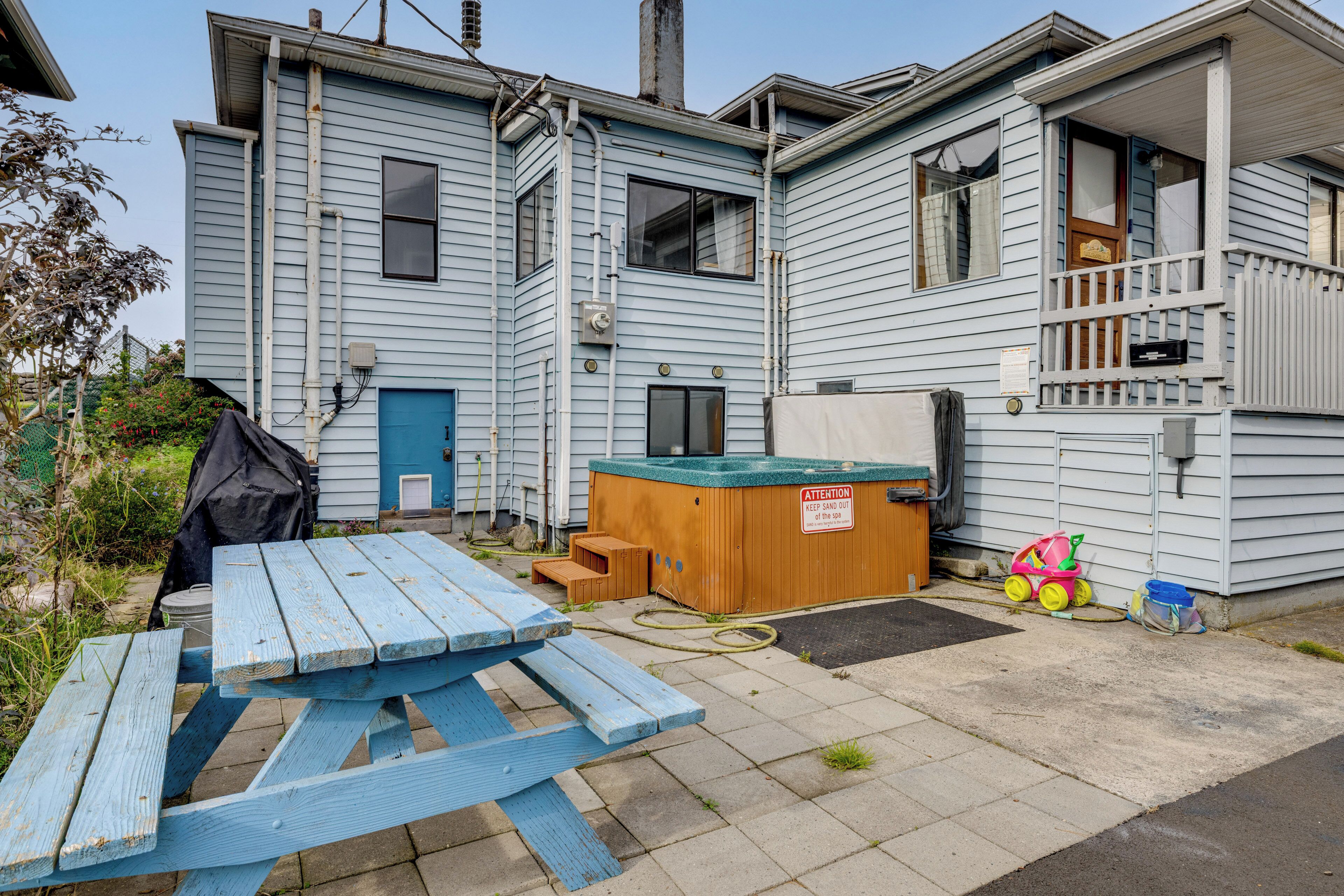 Un edificio de dos pisos con una terraza de madera y una mesa de picnic al frente.