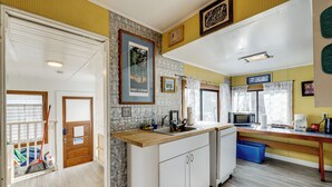 A modern kitchen with a wooden countertop, white cabinets, and a built-in microwave. - Beachfront Cottage on Seaside Promenade w/ Hot Tub (Seaside)