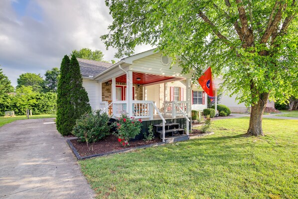 A house with a porch, a flag, and a well-maintained lawn.