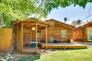 Una cabaña de madera con un porche cubierto, antenas parabólicas y una pequeña mesa y silla.