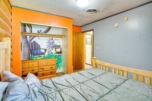 Un dormitorio con cama, cómoda de madera y una puerta que da a otra habitación.
