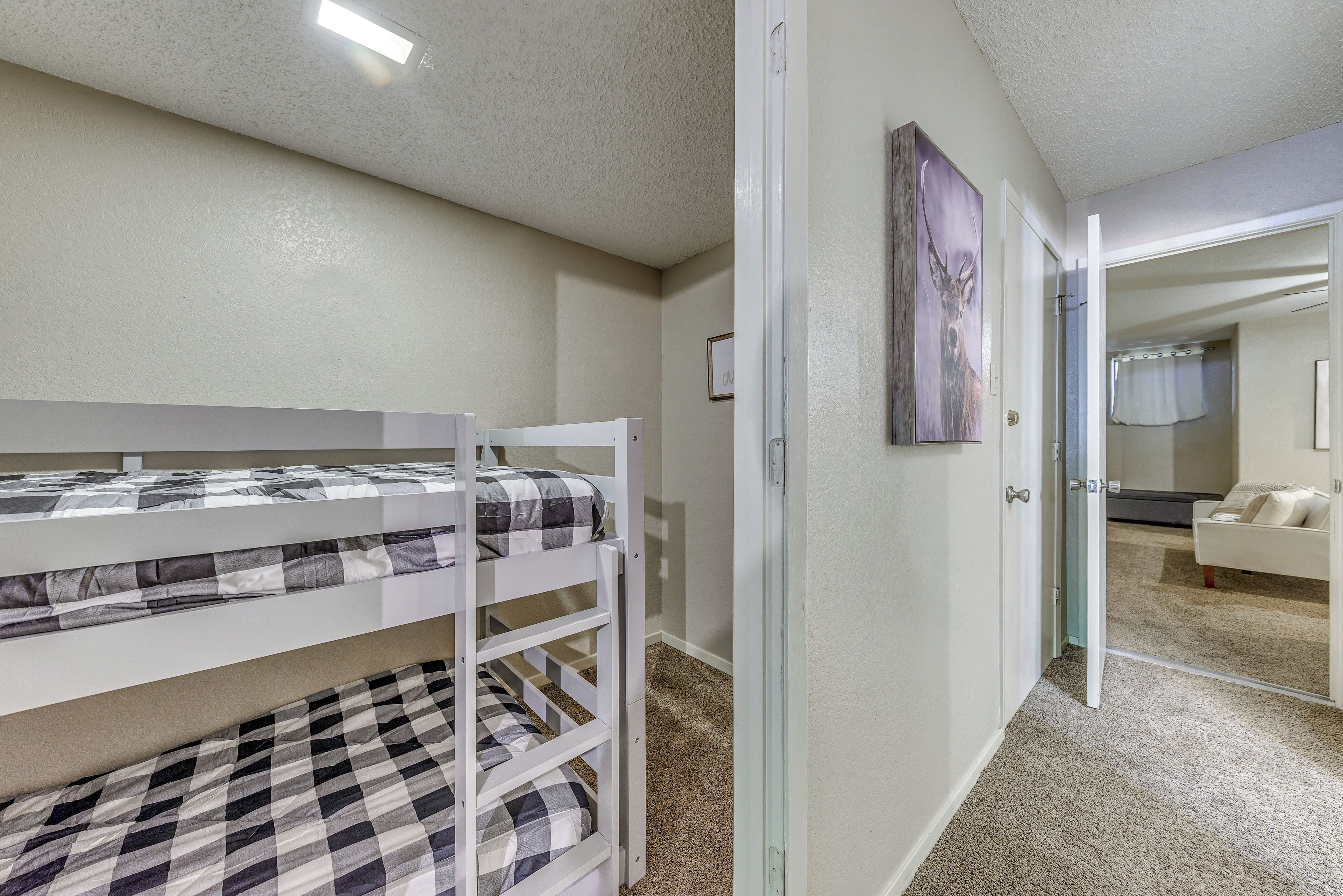 A bedroom with a bunk bed, a glass door leading to another room, and a framed picture on the wall.