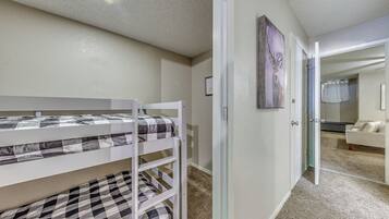 Ein Schlafzimmer mit einem Etagenbett, einer Glastür, die in einen anderen Raum führt, und einem gerahmten Bild an der Wand.